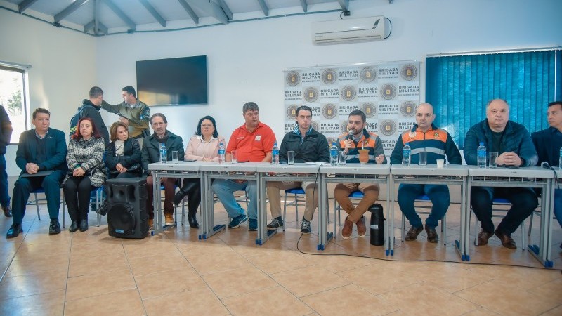 Bancada com o vice-governador falando ao microfone e com participantes, secretários de Estado, defesa civil e prefeitos.