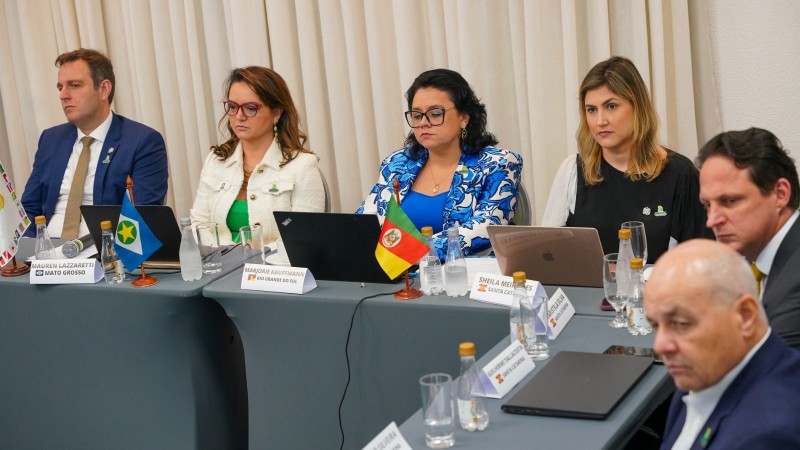 Plano geral dos secretários de estado acomodados em torno de mesa em formato de ferradura. Foco na secretária Marjorie da Sema.