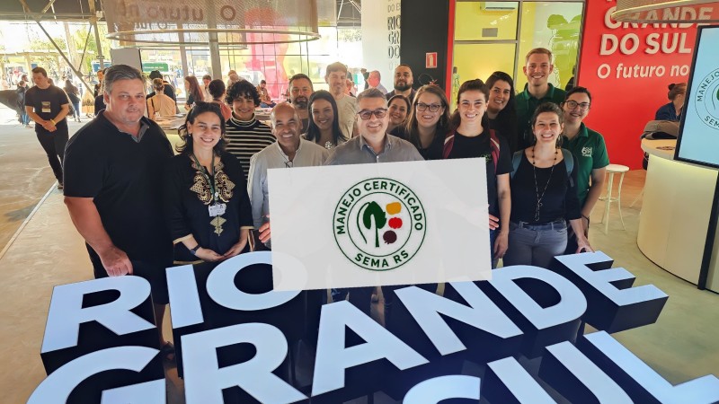 Equipe da Sema posicioanada à frente do estande na expointer. Secretario Camardelli ao centro com a logomarca do selo de manejo em mãos.