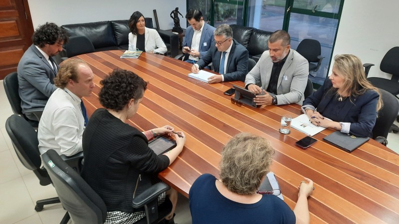 Secretários reunidos, dispostos em cadeiras em torno de uma mesa de formato horizontal.