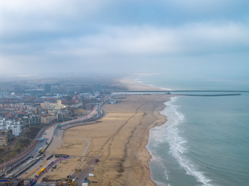 Imagem aérea, de drone, de uma praia com uma larga extensão de areia. O mar fica à direita.