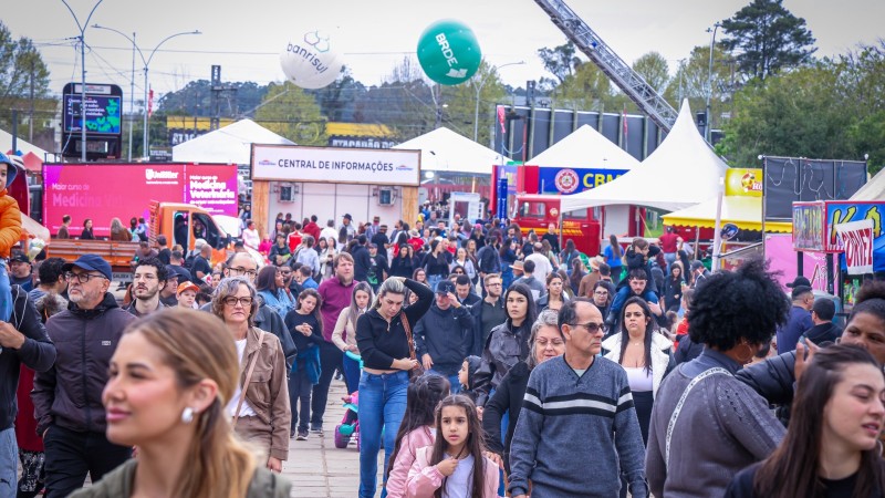 Dezenas de pessoas caminham por estandes de uma feira agropecu&aacute;ria
